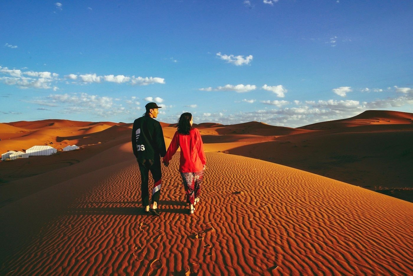 Travelers walking across Erg Chebbi dunes